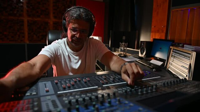 Senior hispanic music producer working on a mixing soundboard in a studio