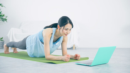パソコンを見ながらトレーニングする女性　プランク　体幹トレーニング