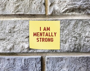 Note stick on rough wall with text I AM MENTALLY STRONG, to remind self to have positive...