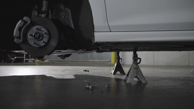 Gimbal shot of car without wheel elevated with jack stands in a workshop, concept of car repair