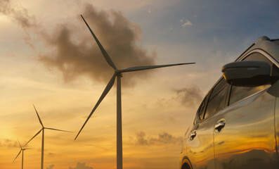 Close-up car in with wind turbines and sunset backgrounds. © Thanumporn