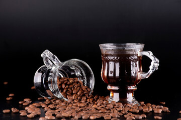 two fancy glass cup hot coffee real brazilian arabica roasted beans spilled and scattered on black background horizontal landscape in close-up - obrazy, fototapety, plakaty