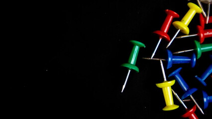 multicolored thumbtacks on a black background