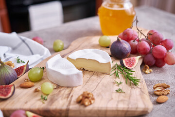Sliced Camembert or brie cheese on wooden cutting board at domestic kitchen