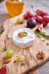 Camembert or brie cheese on wooden cutting board at domestic kitchen