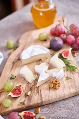 Sliced Camembert or brie cheese on wooden cutting board at domestic kitchen