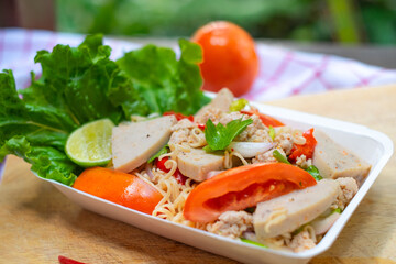 Close up look of hand holding a faom plate of Instant noodle spicy salad with spice, Pork, sausage and vegetable ,Spicy Noodle Salad, Mama Noodle Salad, Yum Mama, Thai Street Food. Asian food.