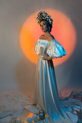 Creative photo of a beautiful model in the image of a snow queen on the background of a glowing circle. Winter fairy tale. A fabulous image. Full-length portrait.