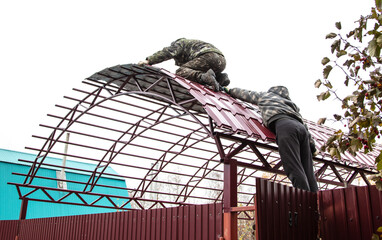 Workers cover the canopy with metal sheets.