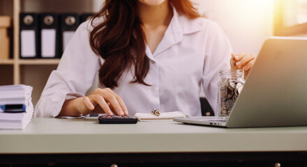 Young business woman sitting in office at table and using smartphone. On desk is laptop and tablet computer, on screen charts and graphs. Woman analyzing data. Student learning online.