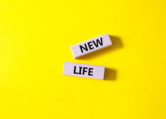 New life symbol. Wooden blocks with words New life. Beautiful yellow background. Business and New life concept. Copy space.
