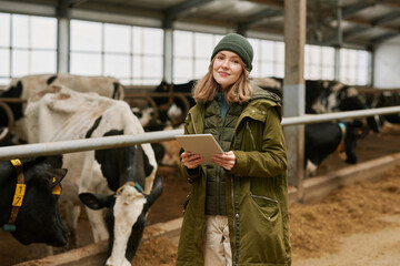 Portrait of young farmer using digital tablet to watch information about each milk cow during her...