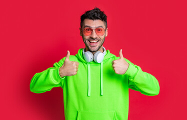 photo of cool music man show thumb up. cool man listen music isolated on red background.