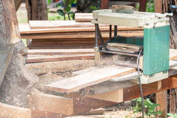 Joiner, Man's hand scouring a wooden board on a thickness machine in garden. Carpenter working with electric planer on wooden beam, plank.DIY concept