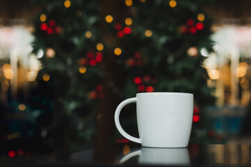 Mug of coffee on table with Christmas light in background.
