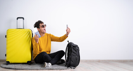 Cheerful traveler tourist man sit on floor using mobile phone booking hotel taxi, making selfie, video call, hold passport tickets isolated on white background. Passenger travel on weekend.