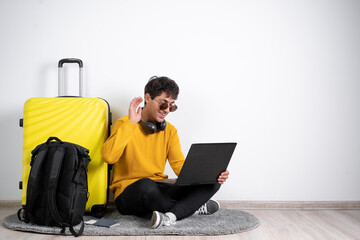 Traveler tourist man in casual sweater near suitcase valise hold laptop pc computer having video call isolated on white background. Passenger travel abroad. Air flight journey