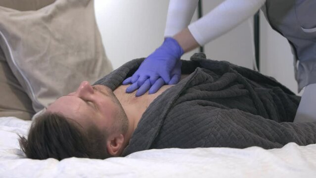 female nurse performing cardiac massage on caucasian male laid on bed room hospital clinic