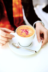 A woman's hand and a cup of rose latte