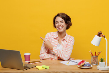 Young happy employee business woman wear casual shirt sit work at office desk with pc laptop point...