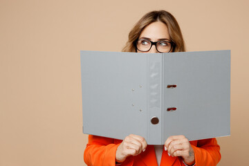 Young employee business woman corporate lawyer wear classic formal orange suit glasses work in office cover mouth with grey folder for papers document bookkeeping isolated on plain beige background.