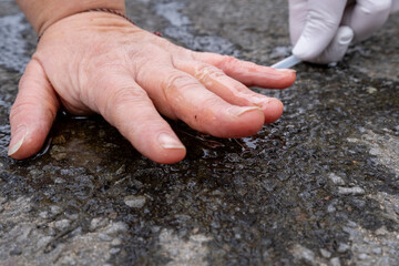 Climate activist stuck his hand on asphalt. Security personnel detach the hand from the road.