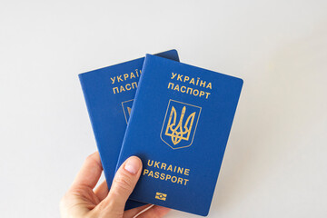 Two Ukrainian passports in a woman's hand on a white background