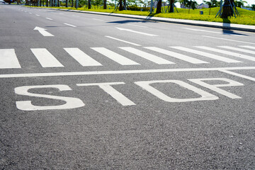 White sign STOP written on asphalt road outdoors. Crossing on the street