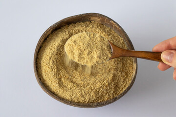 Nutritional yeast in a wooden bowl with spoon. Healthy vegan food concept.