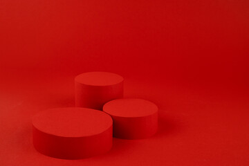 Three red cylinder podiums mockup on rich saturated background for presentation cosmetic products,...