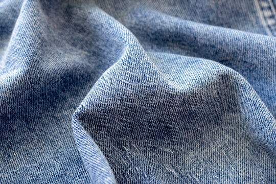 The texture of blue denim folded in waves in close-up