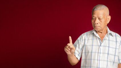 Naklejka premium Senior man in a white shirt showing a finger with a smile while standing on a red background