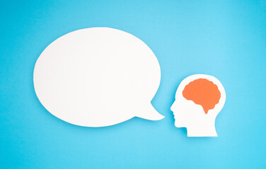 White speech bubble and a brain symbol made from paper on a blue background