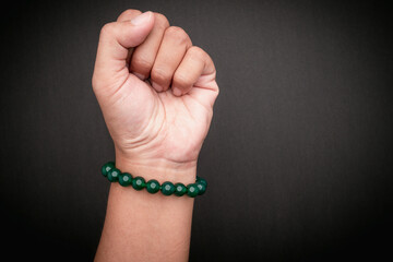 Jade bangle or bracelet on wrist against a black background