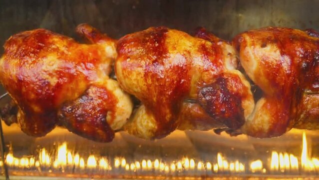 Grilled chicken with a golden crust is spinning on a skewer. High quality FullHD footage