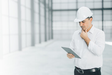 warehouse manager with tablet and ..radio communication his worker working in background in...