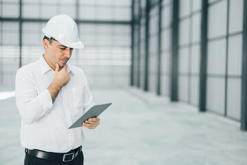 warehouse manager with tablet and ..radio communication his worker working in background in...