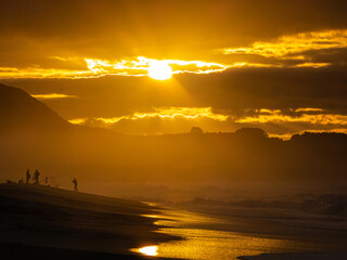 Beautiful sunset on the beach of Valdoviño Spain, with the silhouette of fishermen and orange colors.