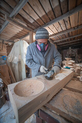craftsman carves the plates out of wood by hand