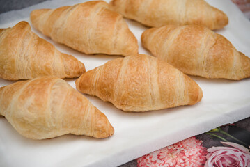 Freshly backed french croissants shiny in the rays of the morning sun close up. 