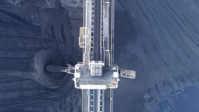 Top down drone shot of Coal Mine Plant, Coal coming off conveyor belt with caterpillar mining trucks moving the coal around. Shot near Gladstone QLD Australia. 4K slow motion