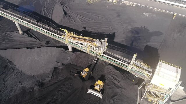 Drone orbiting shot of Coal Mine Plant, Coal coming off conveyor belt with caterpillar mining trucks moving the coal around. Shot near Gladstone QLD Australia. 4K slow motion