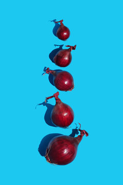 Red onion vertical composition on bright blue background. Top view flat lay composition. Minimal concept with harsh light and sharp shadow