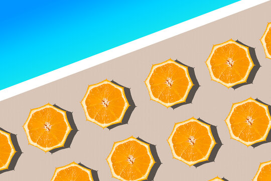 Minimal summer vacation concept. Areal view of sun umbrellas made of fresh orange halfs on the sandy beach near the blue sea.