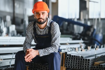 Happy Professional Heavy Industry Engineer Worker Wearing Uniform, and Hard Hat in a Steel Factory. Smiling Industrial Specialist Standing in a Metal Construction Manufacture - obrazy, fototapety, plakaty