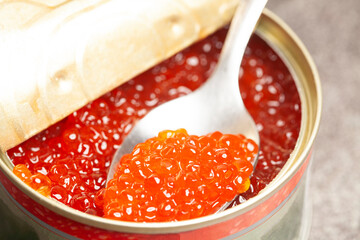 Metal can and spoon with delicious red caviar isolated on white background.