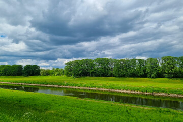 View of the river before a thunderstorm. The background of nature and green meadows.