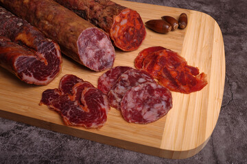 Iberian sausage, Iberian chorizo and Iberian loin on cutting board and wooden table, garnished with acorns