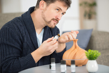 man with diffuser smelling aromatherapy oils