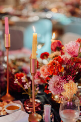 Festive table served with cutlery and fresh flowers on which there is a burning candle